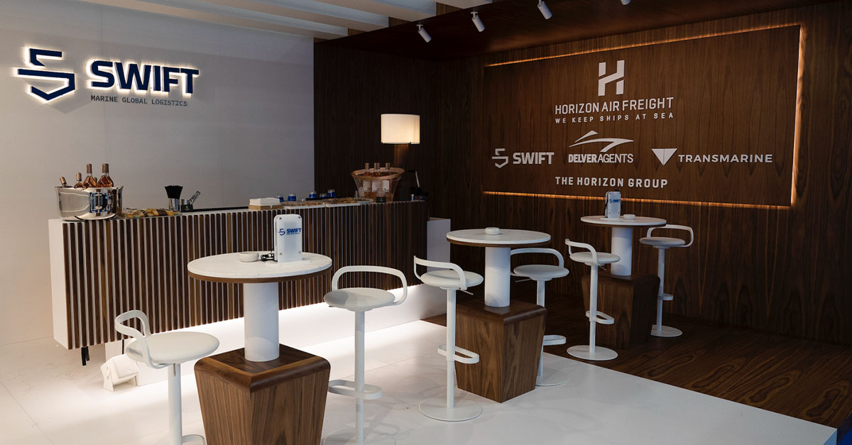 A room with chairs and tables, a Swift Marine logo on the wall, along with the whole logo soup for the Horizon Air Freight brands.